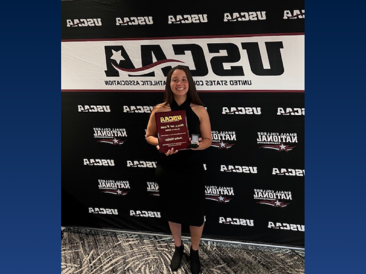 A college student holding an award