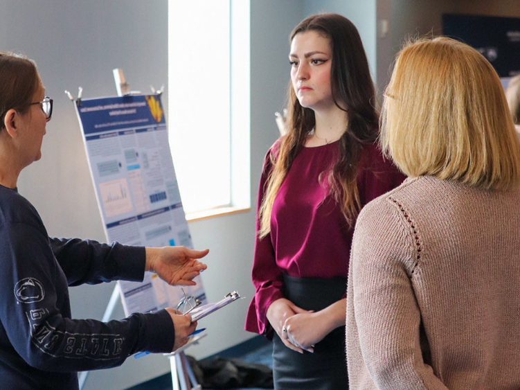 A student speaking with two judges in a classroom 